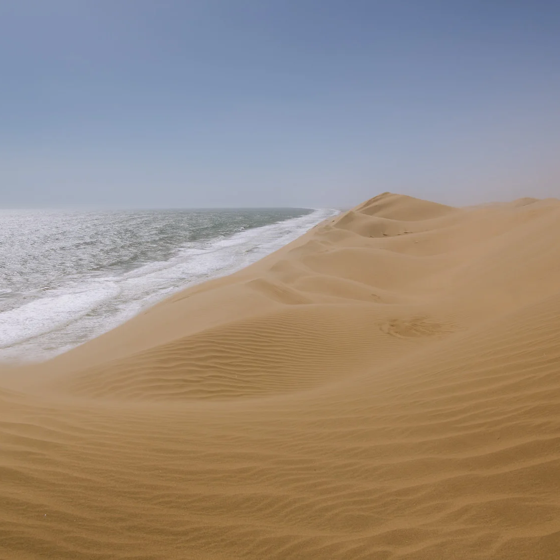 sand dunes meet the ocean at sandwich harbour