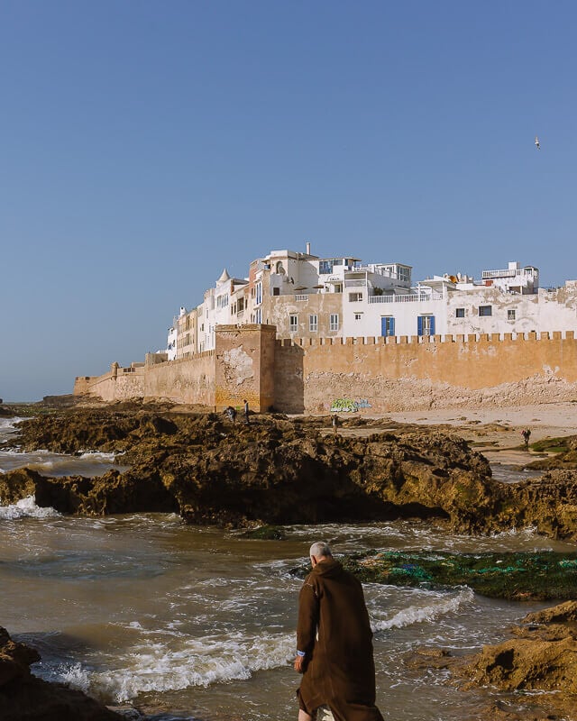 man stands in front of the sea walls in Essaouira Moroco