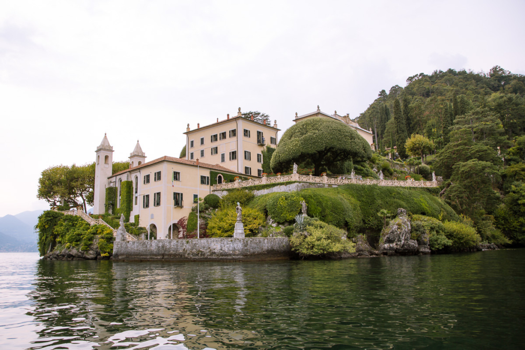 mansion with manicured garden set beside a lake.