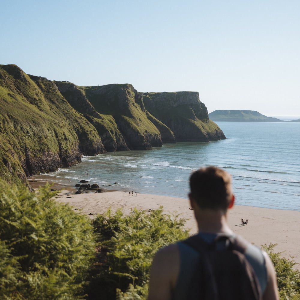 standing in front of a wide sandy beach with cliffs reaching the sea