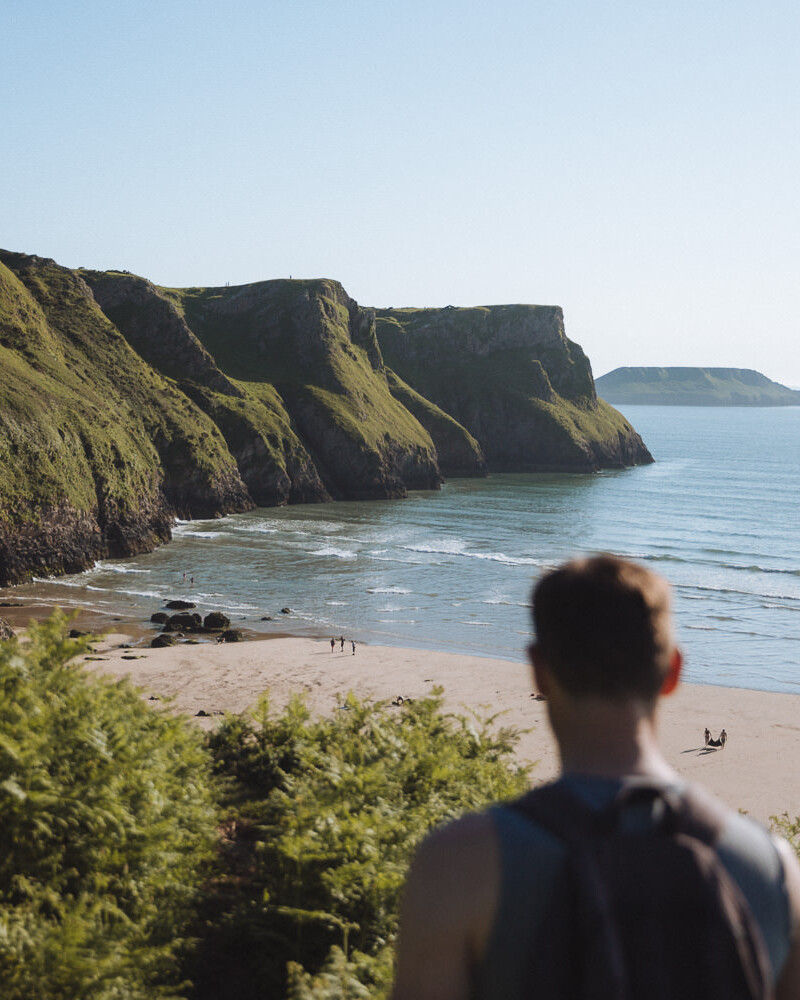 standing in front of a wide sandy beach with cliffs reaching the sea