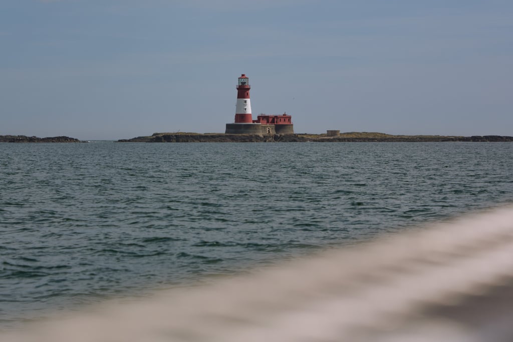 red and white lighthouse on the horizon with sea in the foreground