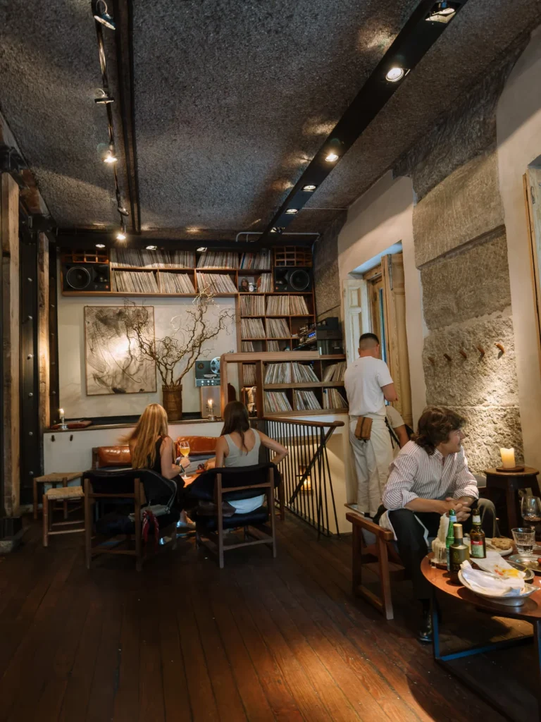 Customers inside a stylish Madrid bar lined with shelves of vinyl records