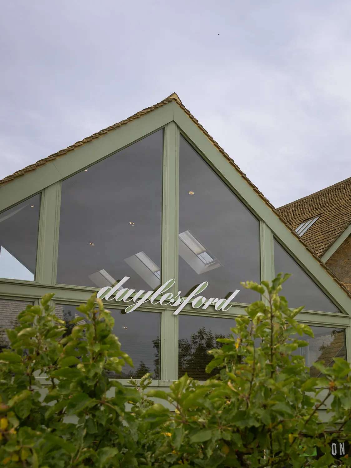 Daylesford Organic farm shop building in the Cotswolds, with its name displayed across the large glass frontage.