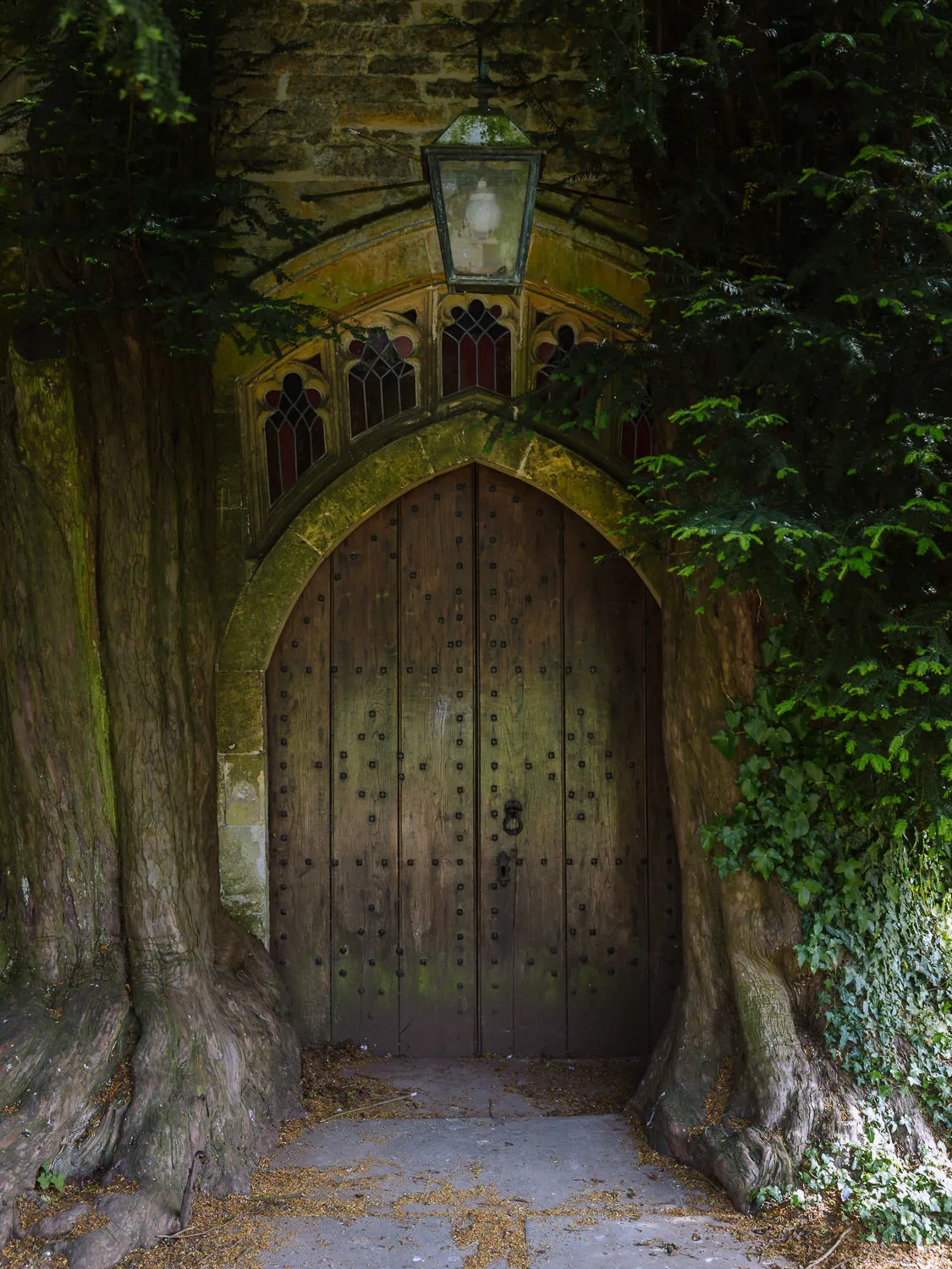 Medieval wooden doorway at St Edward’s Church in Stow-on-the-Wold, framed by ancient yew trees.