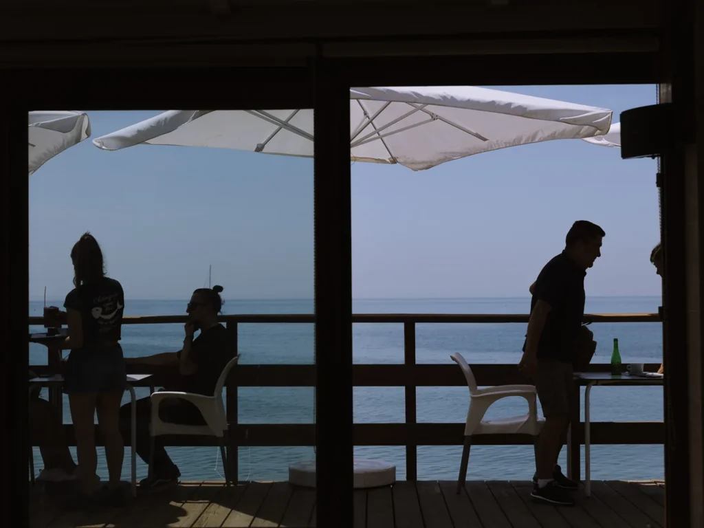 People sitting on a seafront terrace bar overlooking the Mediterranean Sea on the Costa del Sol, Spain