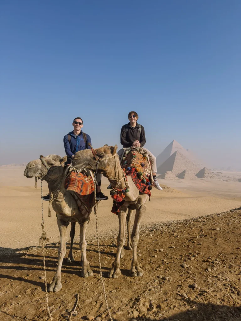 paul and mark on camels in front of the pyramids