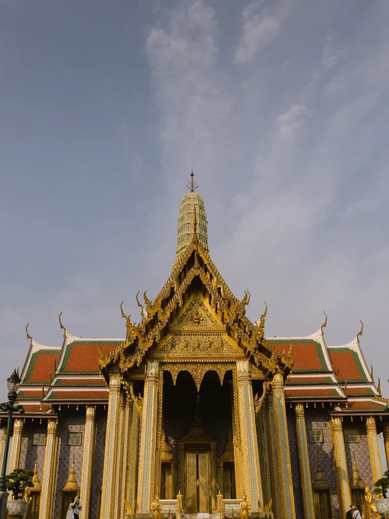 Golden tiered spire and ornate roofs of Emerald Buddha Temple at Bangkok Grand Palace.