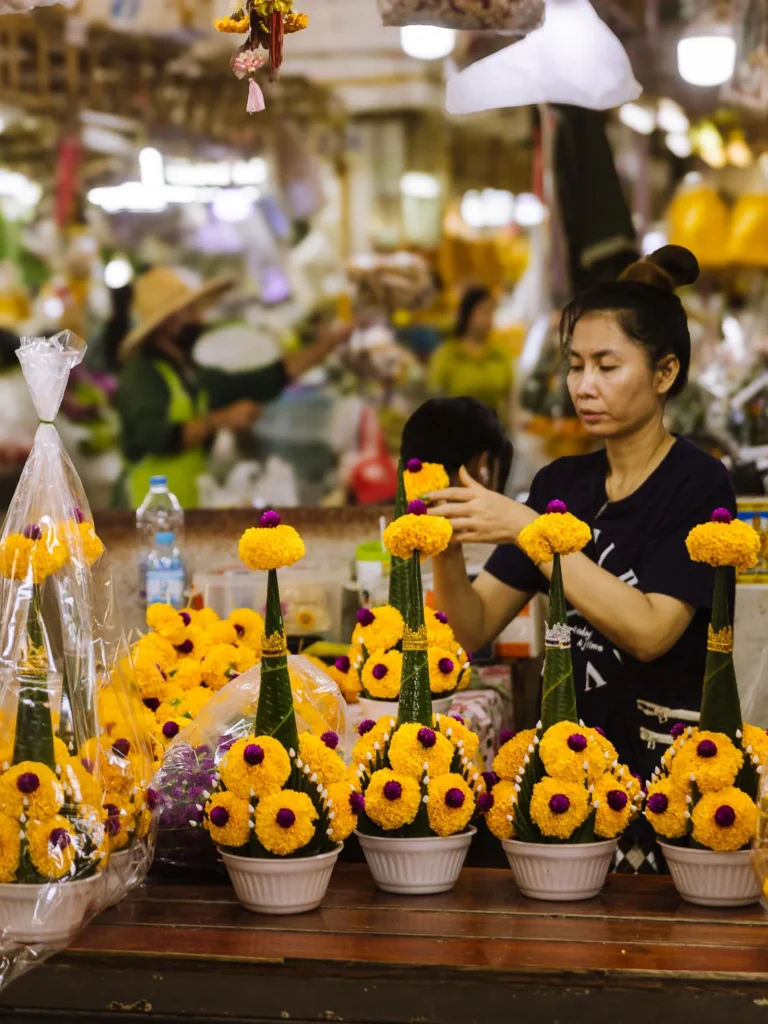 Vendor arranging marigold temple offerings at Pak Khlong Talat flower market, Bangkok