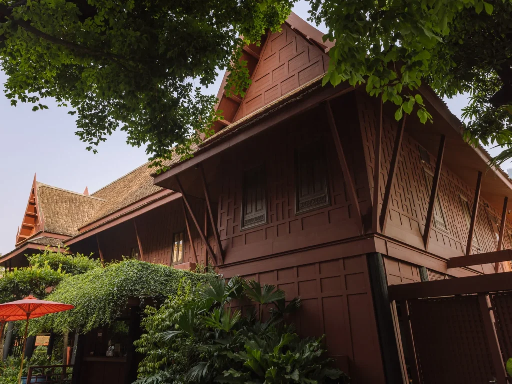 Traditional Thai teakwood house framed by trees at Jim Thompson House Museum in Bangkok.