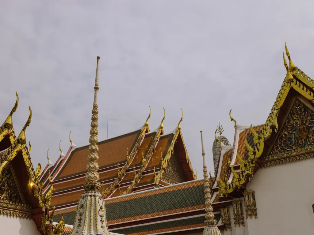 Golden spires and red-tiled roofs of ornate pavilions at Wat Pho Temple, Bangkok.