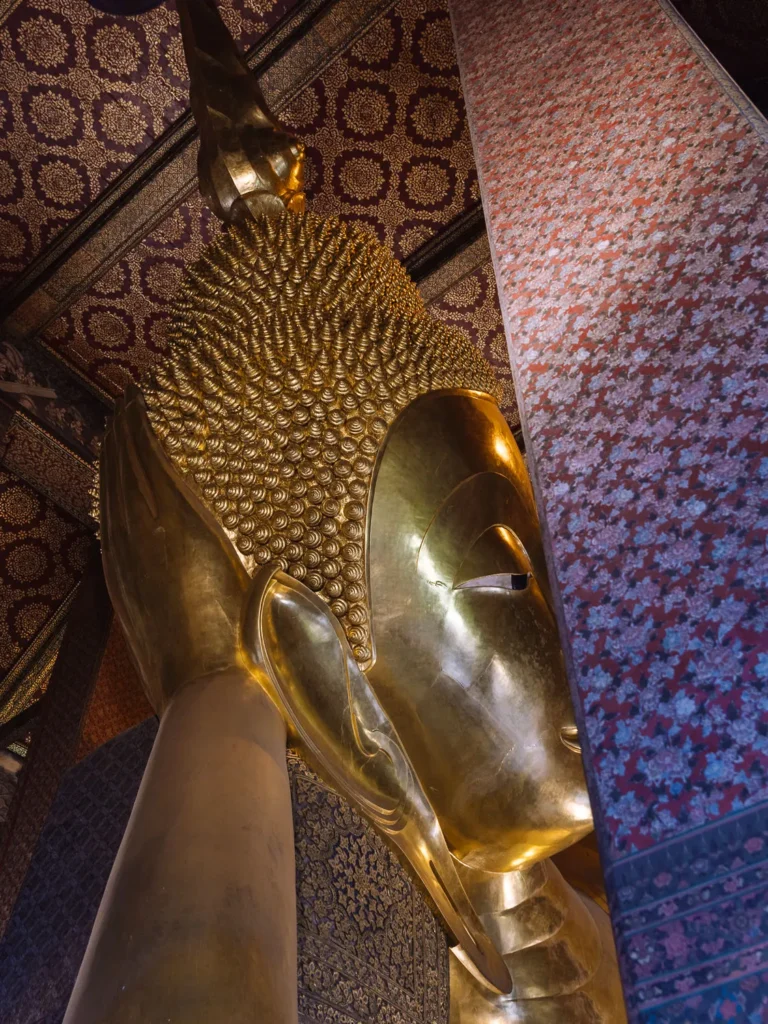 Close-up of Reclining Buddha's golden head and hand at Wat Pho Temple, Bangkok.