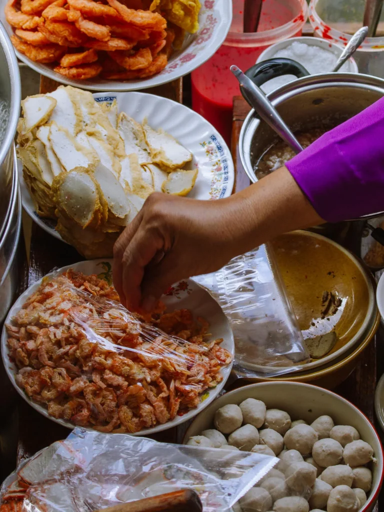 Thai street food ingredients including dried shrimp, fish cakes and meatballs at a Bangkok food tour stall.