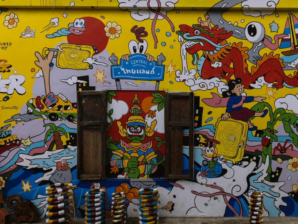 Colourful street art mural featuring Thai mythological figures and cartoon characters on a shophouse wall in Talat Noi, Bangkok