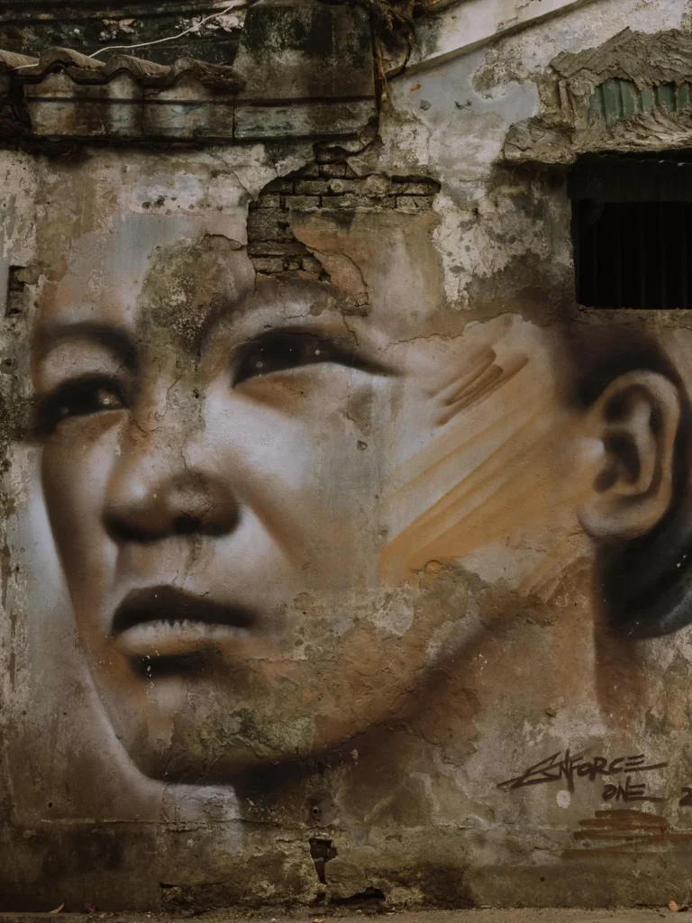 Large-scale photorealistic portrait mural on a crumbling wall in Talat Noi, Bangkok, by street artist Enforce One.