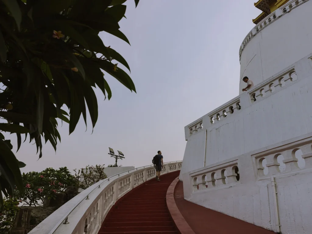 A visitor climbs the red-carpeted spiral staircase winding around the white chedi at Wat Saket, Bangkok.
