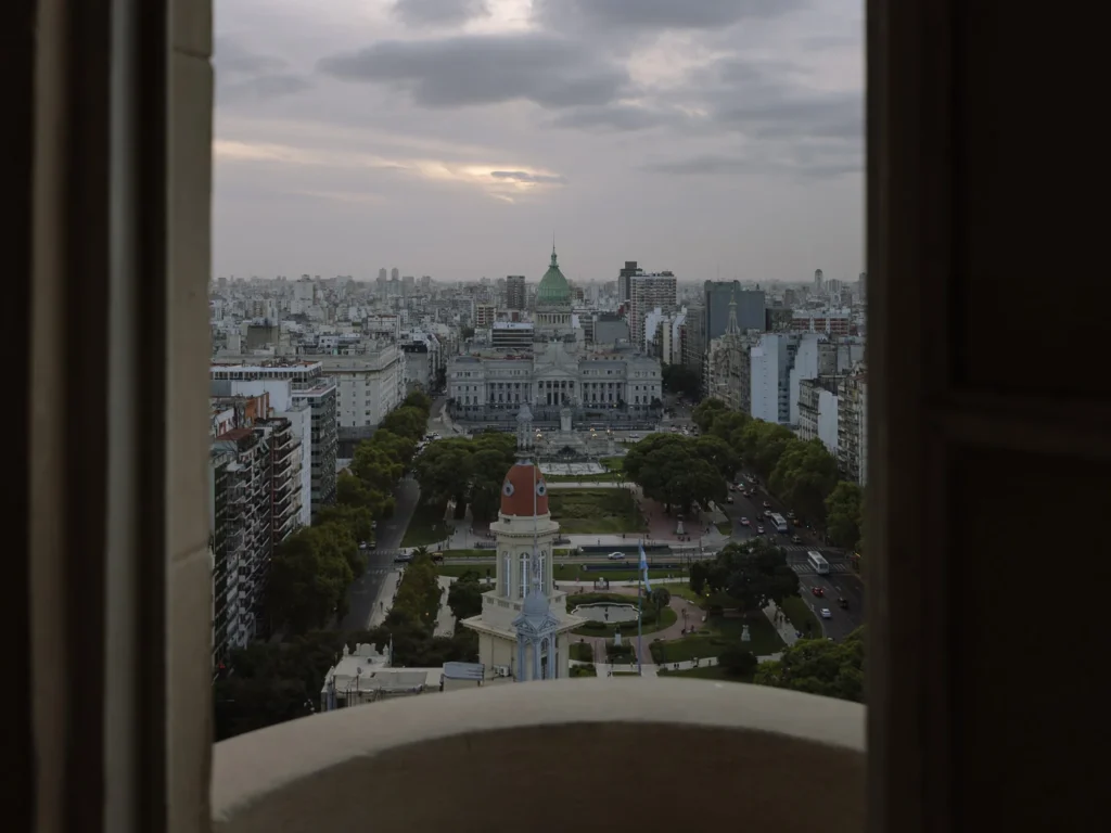 The view from the lighthouse tower of Palacio Barolo in Buenos Aires, looking down the tree-lined Avenida de Mayo towards the green copper dome of the National Congress building at dusk