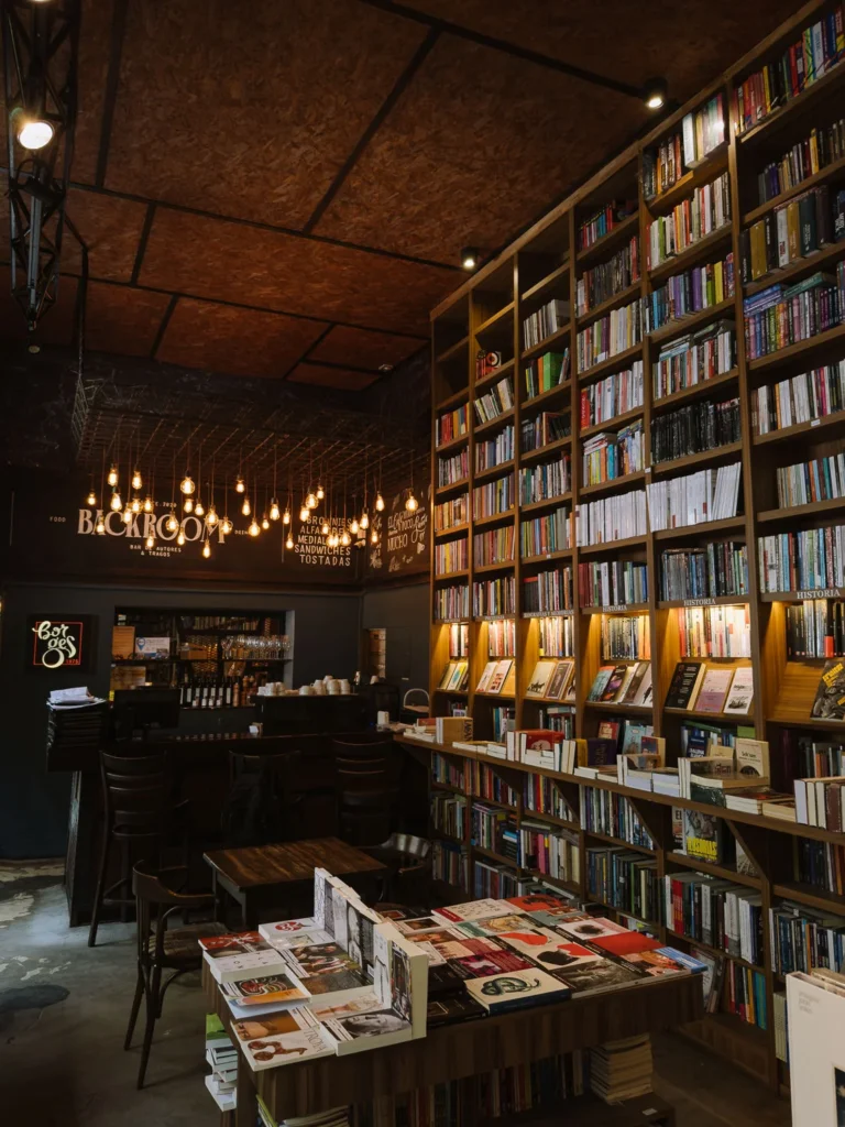 The interior of Backroom Bar in Palermo, Buenos Aires, with floor-to-ceiling bookshelves, pendant Edison bulbs and a bar counter visible in the background