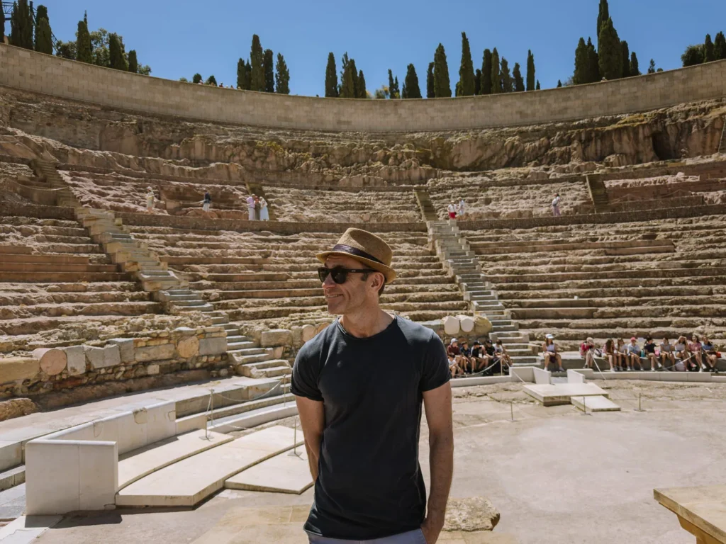 A visitor stands on the ancient stage of the Roman Theatre of Cartagena, Spain — a remarkably preserved 1st-century BC amphitheatre built during the reign of Emperor Augustus, with a capacity of up to 6,000 spectators.