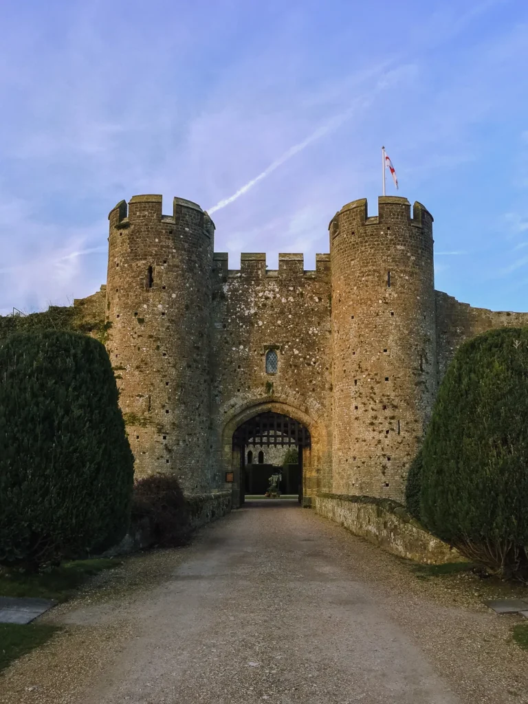 Twin battlemented stone towers flanking the archway entrance to Amberley Castle at dusk