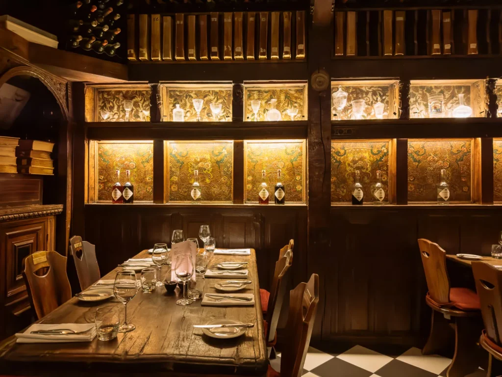 Cozy Amsterdam brown café interior with wooden tables, bottle-lined shelves and warm lighting, showing a long table set for dinner