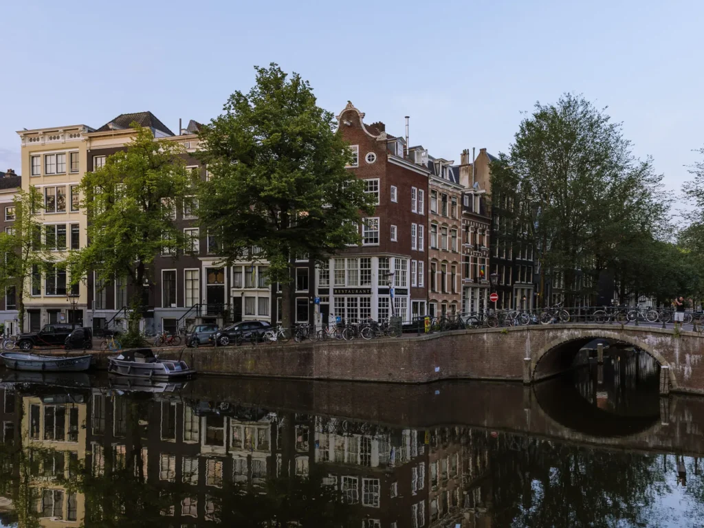 Canal houses, bicycles and a brick bridge reflected in a canal in central Amsterdam