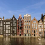 Row of narrow historic canal houses along a waterfront in Amsterdam